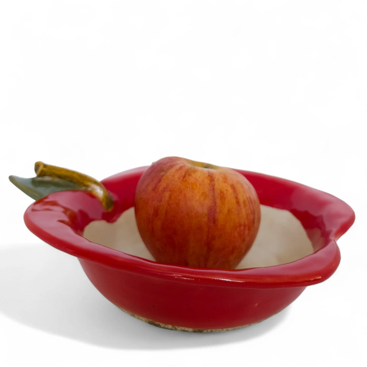 Red apple-shaped baker bowl holding a whole apple, with a cream interior and sculpted leaf and stem
