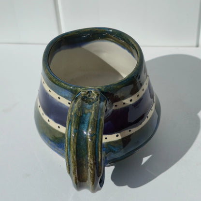 Close-up of the green glazed handle on a green and indigo striped stoneware mug