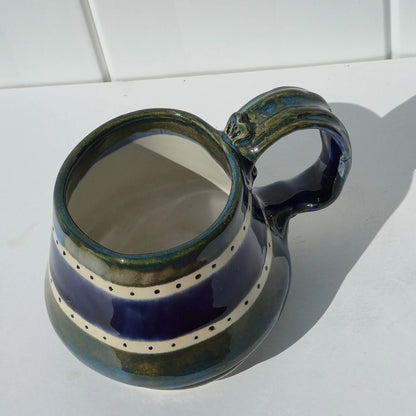 Green and indigo striped stoneware mug viewed from above, with the handle on the right