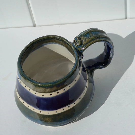 Green and indigo striped stoneware mug viewed from above, with the handle on the right