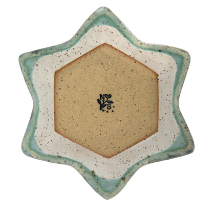 Underside of the Star of David dish with a bare hexagonal clay base, maker’s signature, and blue-green glazed edges.
